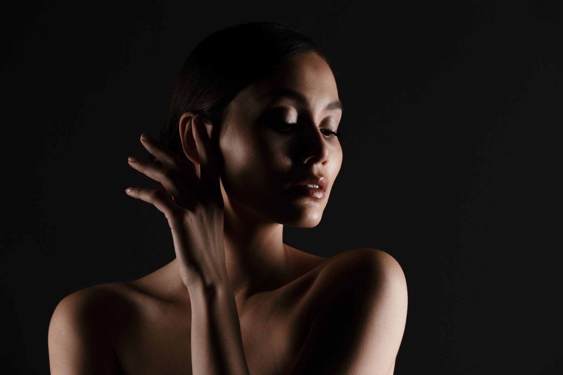 A woman is covering her face with her hand in the dark.