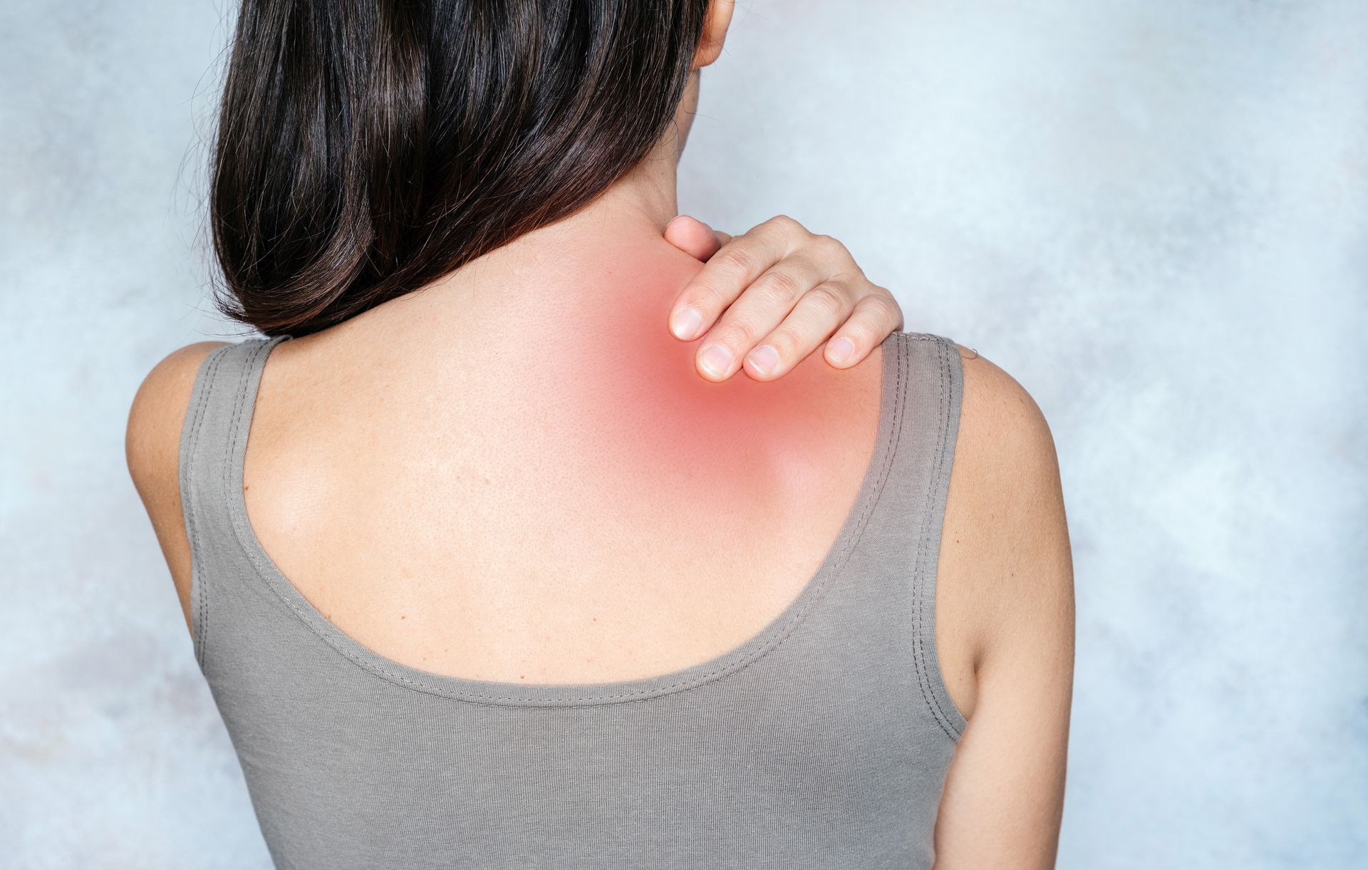 A woman is holding her neck and shoulder in pain.