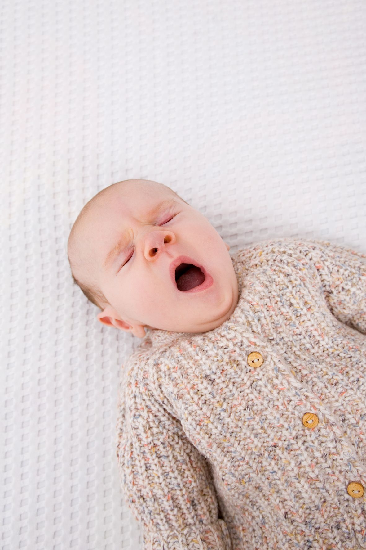 nordwestnord fotografie babyfotoshooting baby liegt auf dem rücken und gähnt