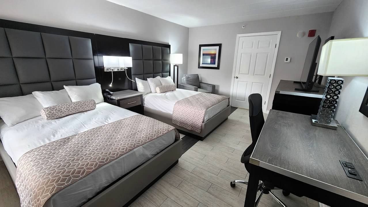 A hotel room with two beds and a desk.