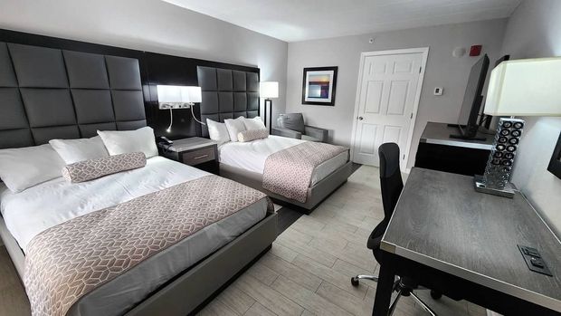 A hotel room with two beds , a desk and a chair.