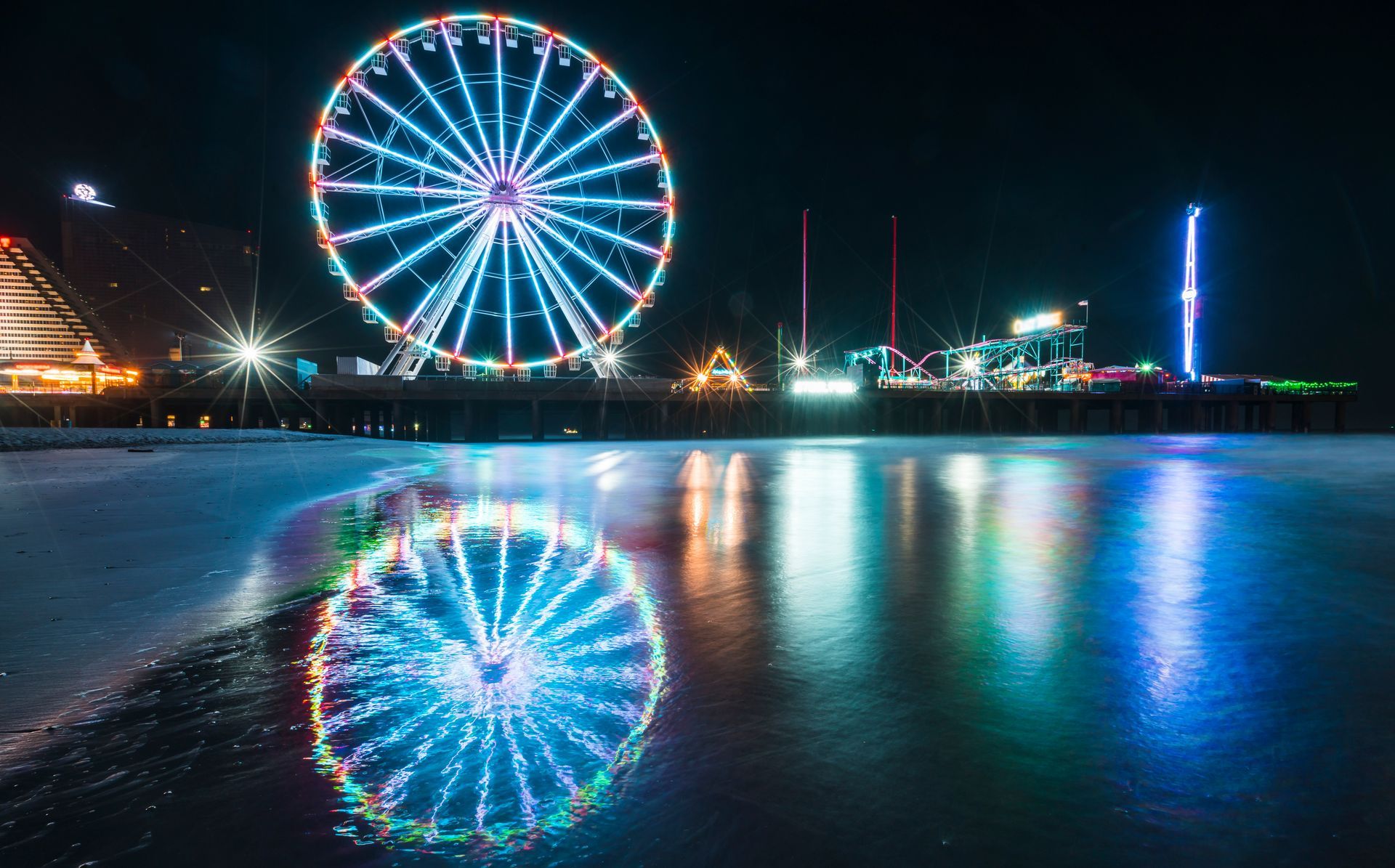 A ferris wheel is reflected in the water at night.