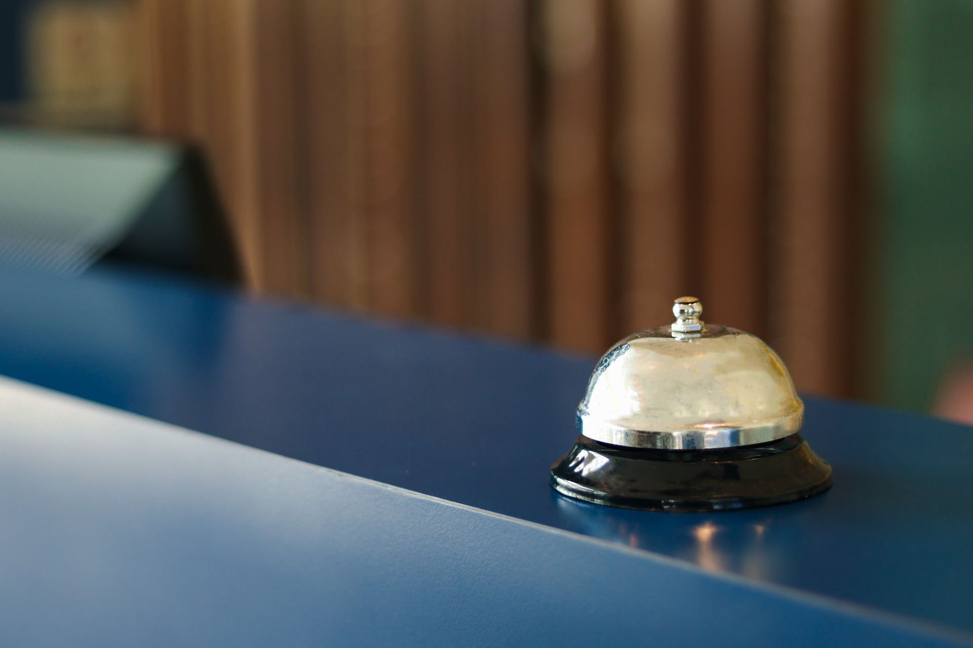 A hotel bell is sitting on a blue counter.