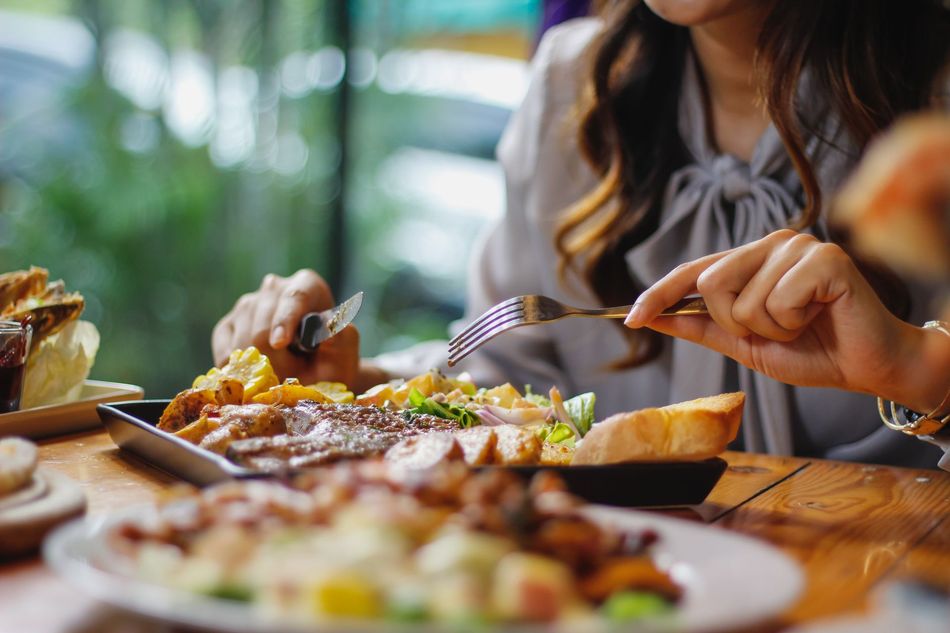 A woman is sitting at a table eating a plate of food.