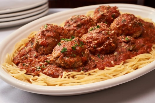 A close up of a plate of pasta with sauce and meatballs