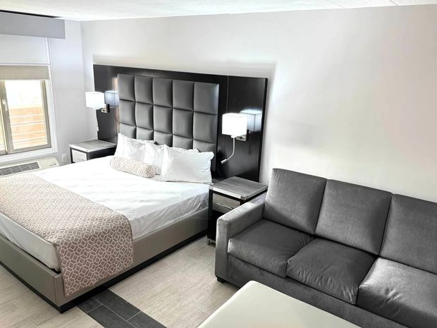 A hotel room with a king size bed , chair , desk and television.