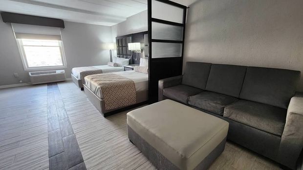 A hotel room with two beds and a couch.