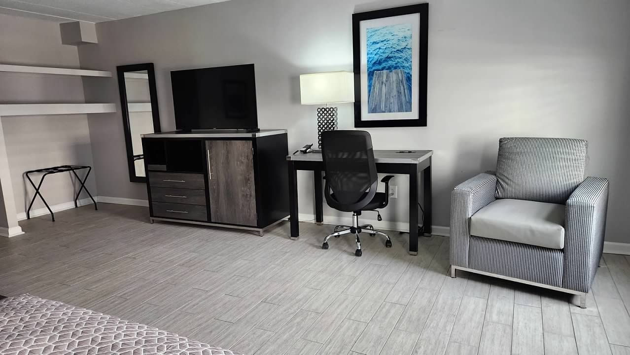 A hotel room with a desk , chair and television.