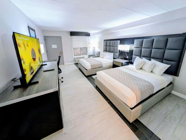 A hotel room with two beds , a desk and a chair.