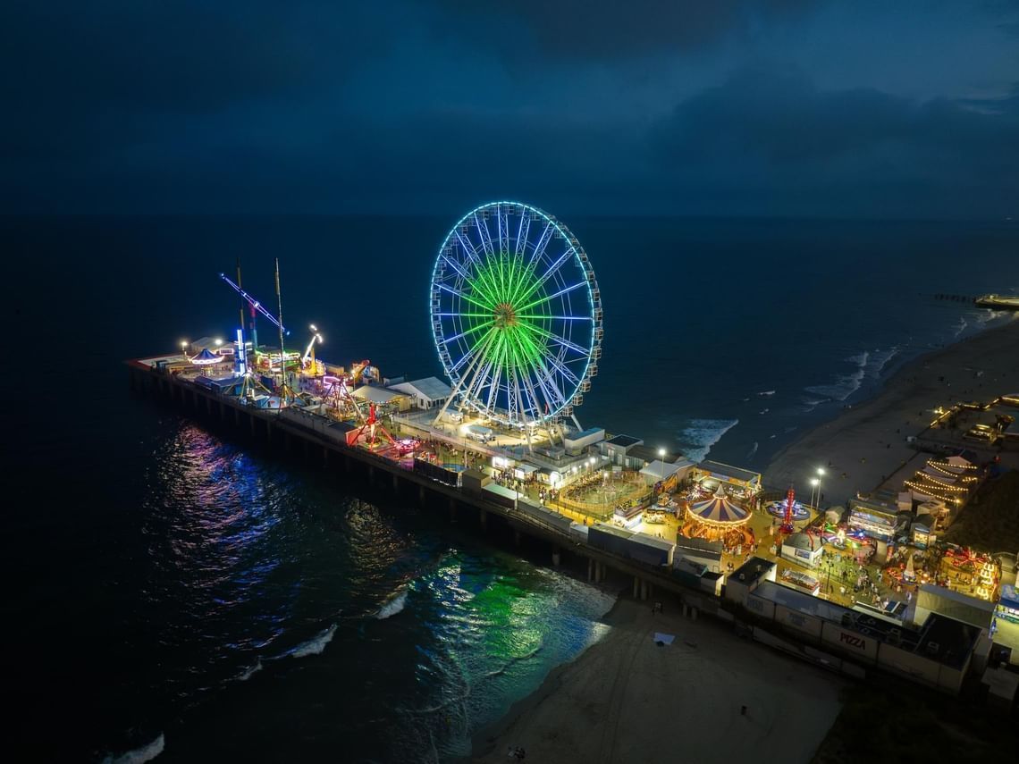 A night time photo of amusement pier with large ferris wheel