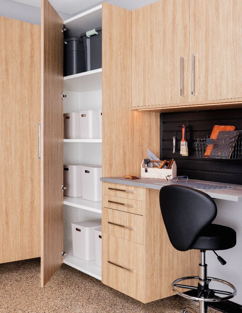 A light wood home office workstation with a tall storage cabinet, drawers, wall-mounted desk, and a black stool.