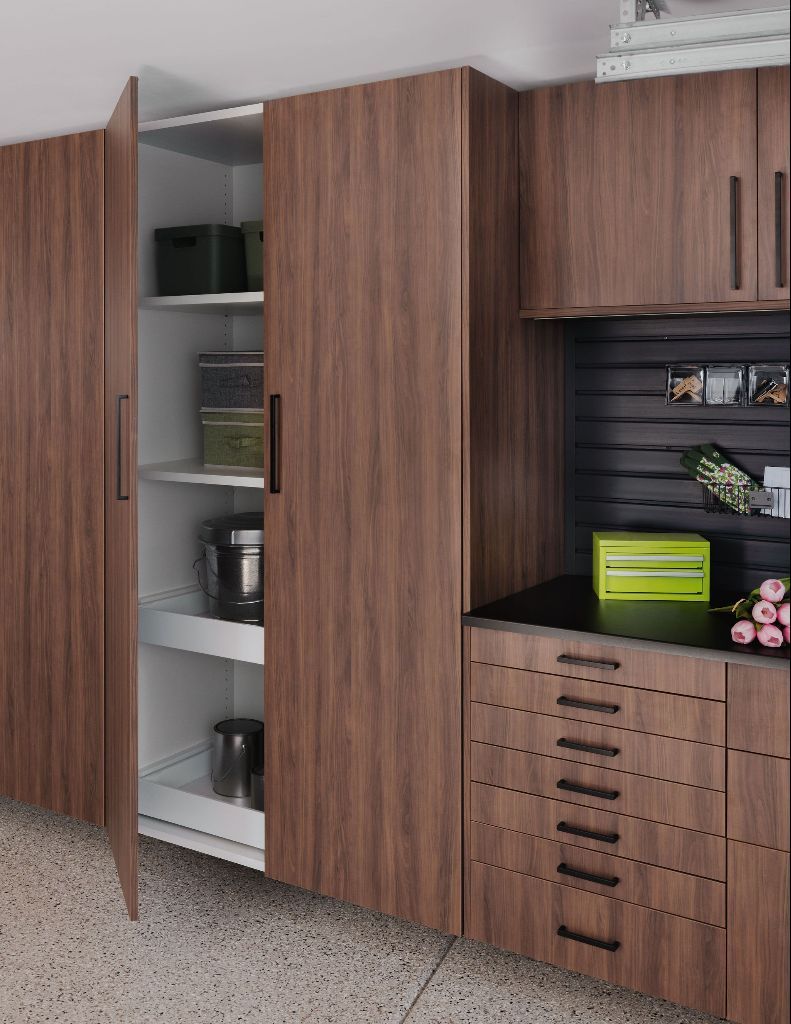 Modern, wood-finish pantry cabinets with sliding shelves, drawers, and a workspace with black slatted wall organization.