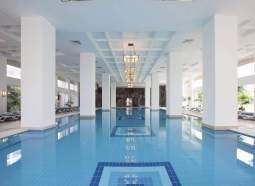 There is a large swimming pool in the middle of a building.