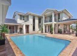 A large white house with a large swimming pool in front of it.