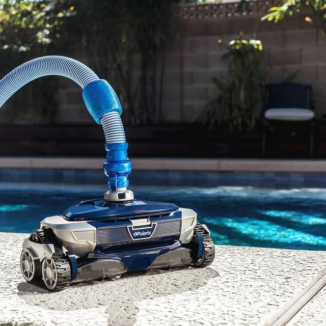 A robotic pool cleaner is sitting on the edge of a pool