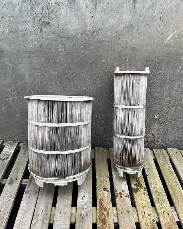 Two wooden barrels are sitting on a wooden pallet.