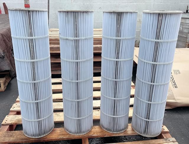 Four white filters are lined up on a wooden pallet