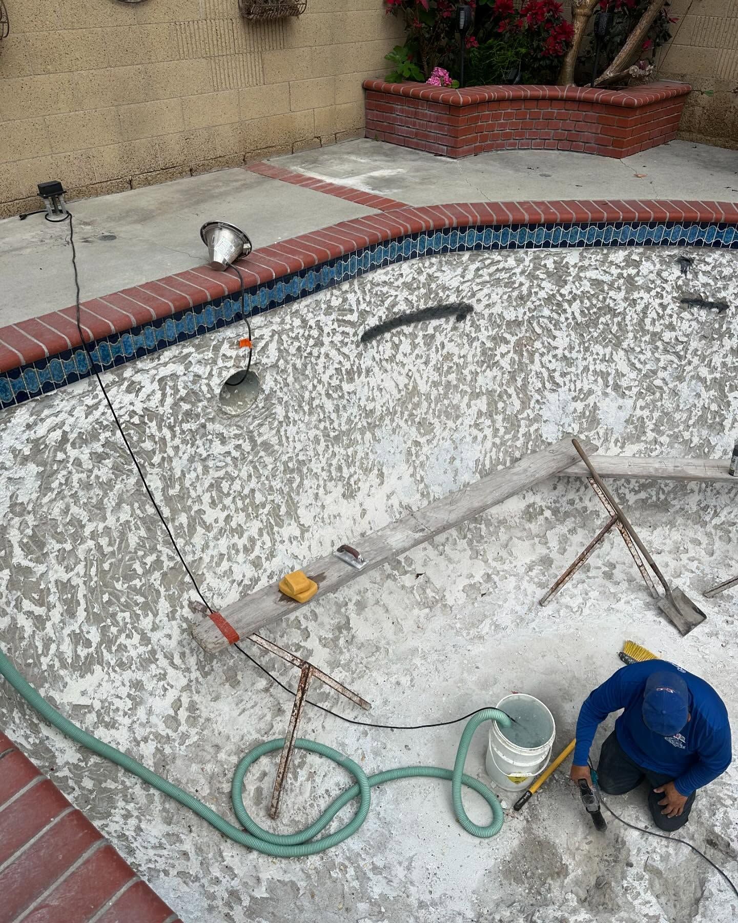A man is working on a swimming pool with a hose.