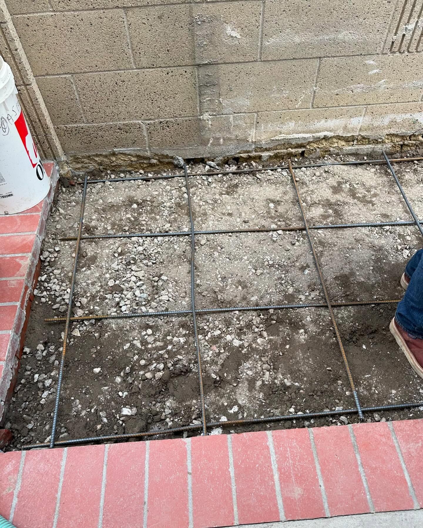 A person is standing on a concrete floor next to a brick wall.