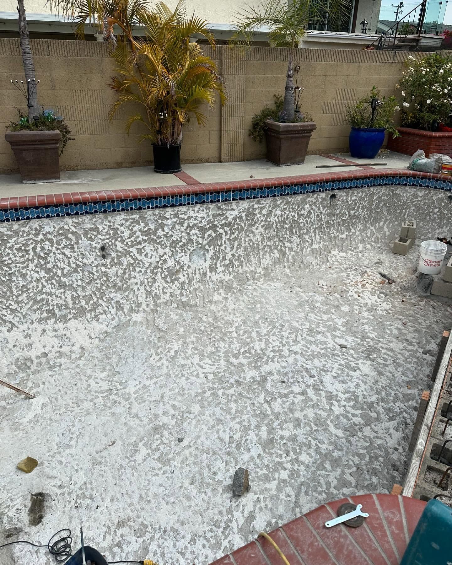 A swimming pool is being remodeled in a backyard.