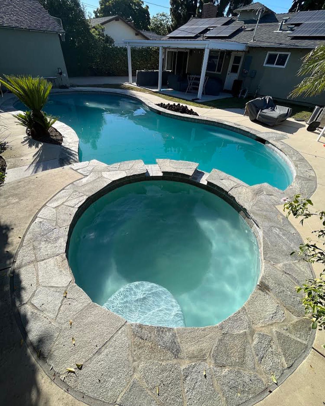 A large swimming pool with a hot tub in the middle of it.