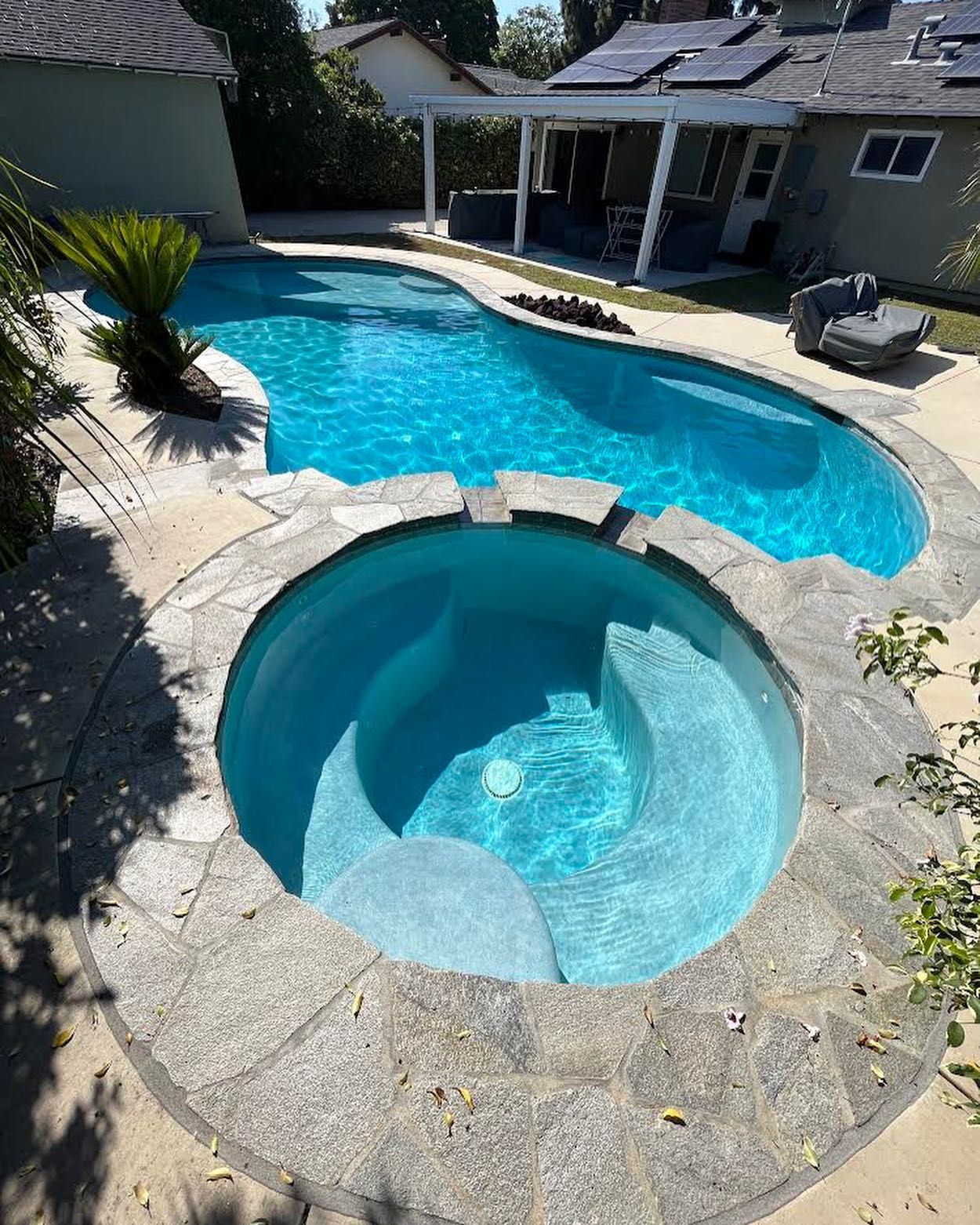 A large swimming pool with a hot tub in the middle of it.