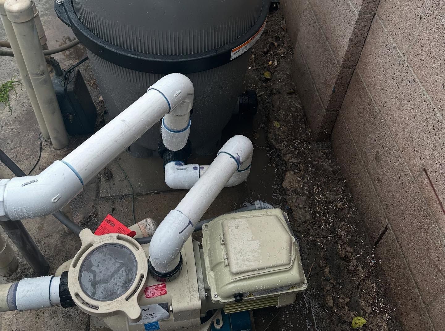 A swimming pool pump is sitting on the ground next to a wall.