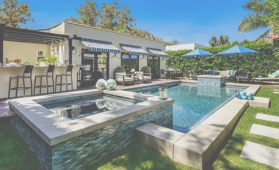 A large swimming pool is in the backyard of a house.