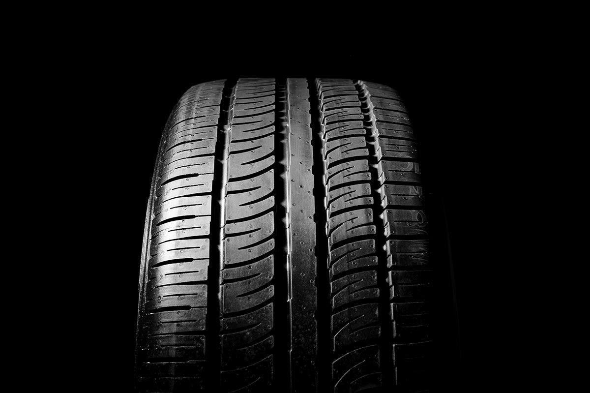 Close-up of a car tire with prominent tread against a black background.