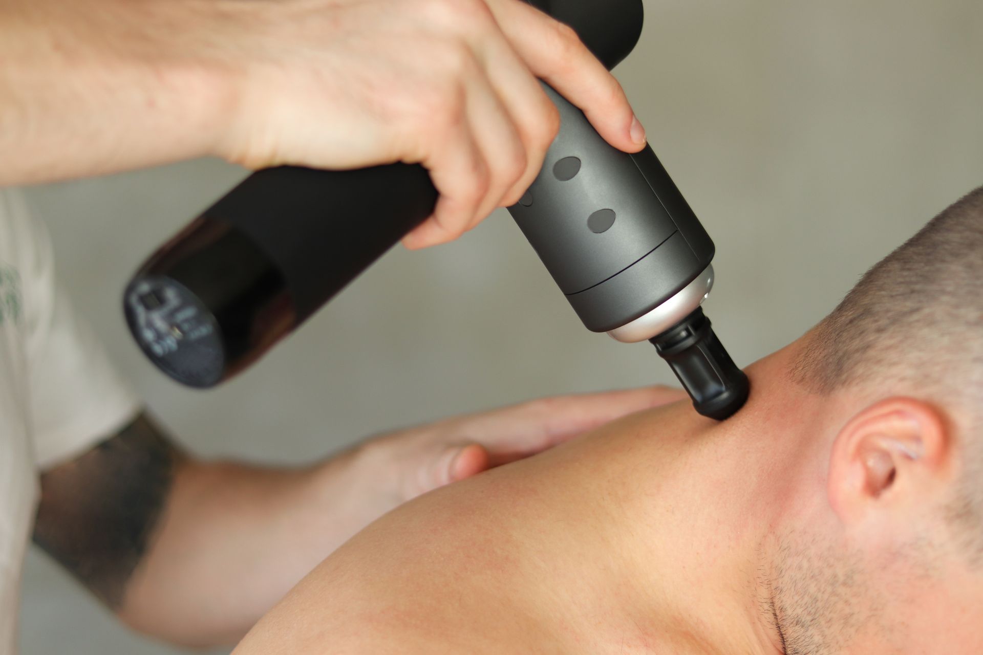 A man is getting a massage with a device on his neck