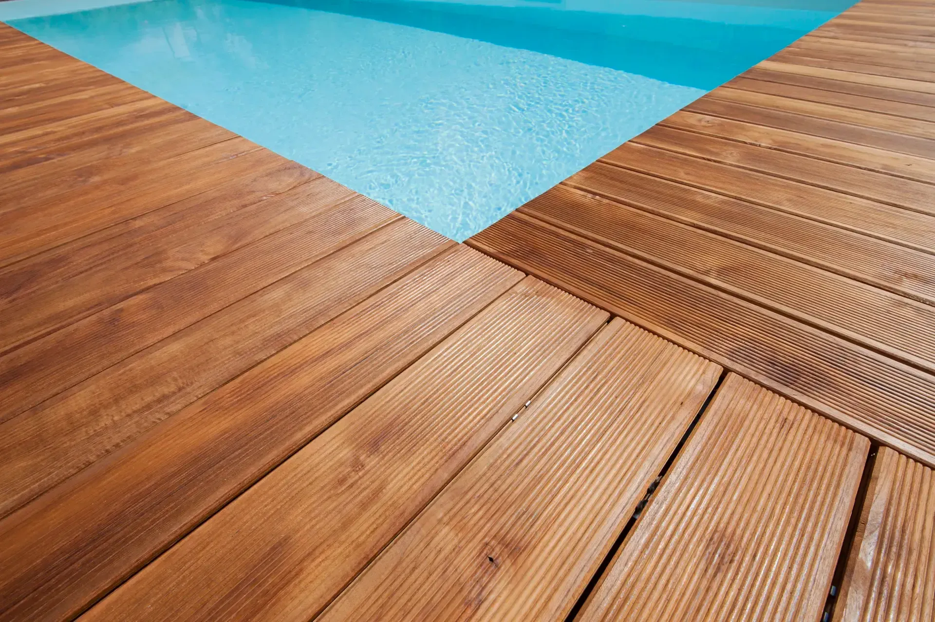 Una terrazza in legno accanto a una piscina.