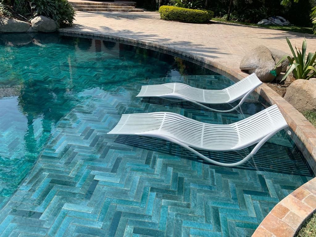 Due sedie a sdraio bianche sono posizionate accanto a una piscina.