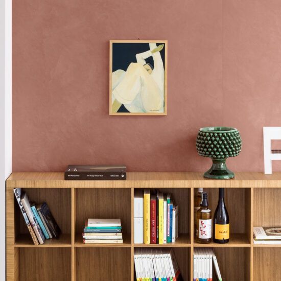 Un'immagine di una donna è appesa a una parete sopra una libreria