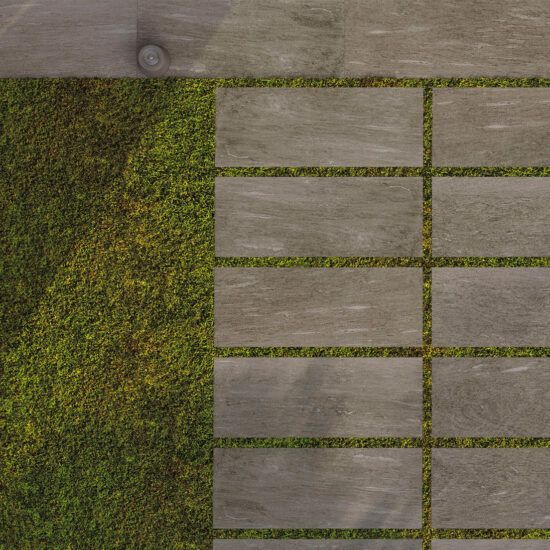 Una vista aerea di un patio con l'erba che cresce tra le piastrelle.