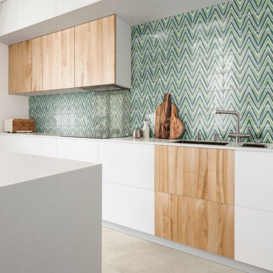 Una cucina con mobili bianchi, mobili in legno, un lavandino e un tagliere.