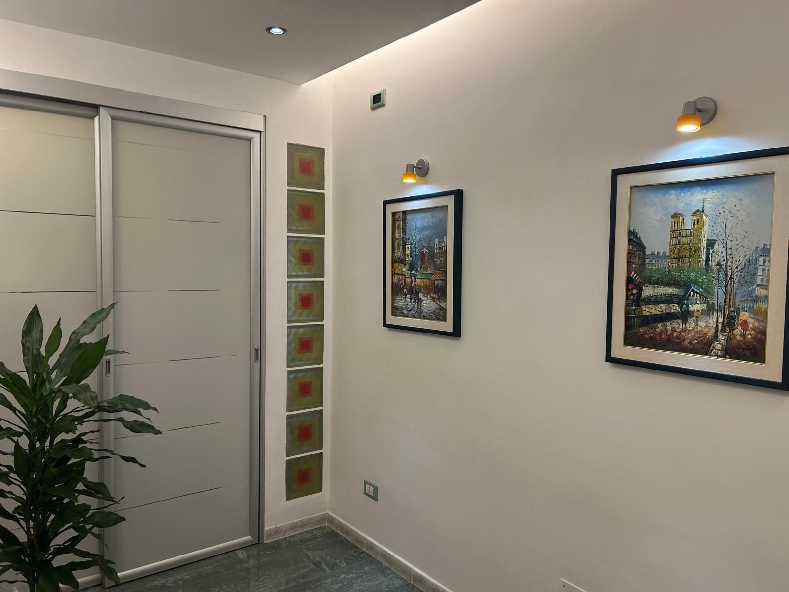 Un corridoio con una pianta e due quadri sul muro.