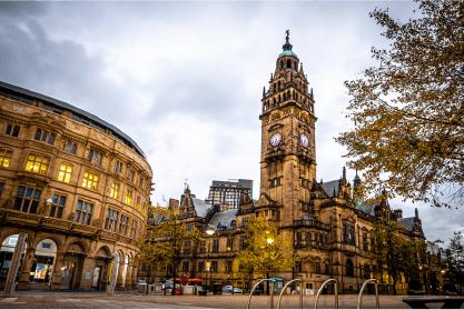 A large building with a clock tower in the middle of a city.