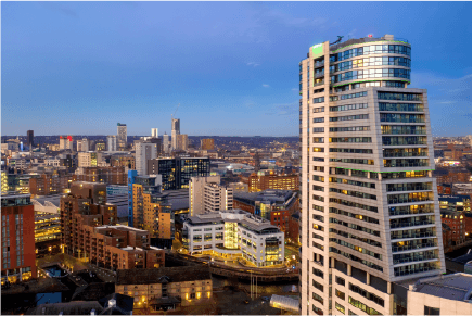 An aerial view of a city at night with a tall building in the foreground.