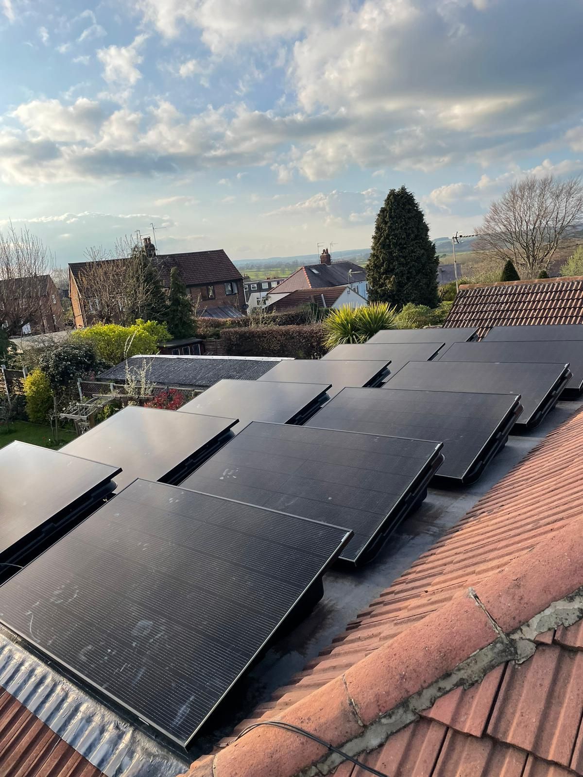 A row of solar panels are sitting on top of a tiled roof.