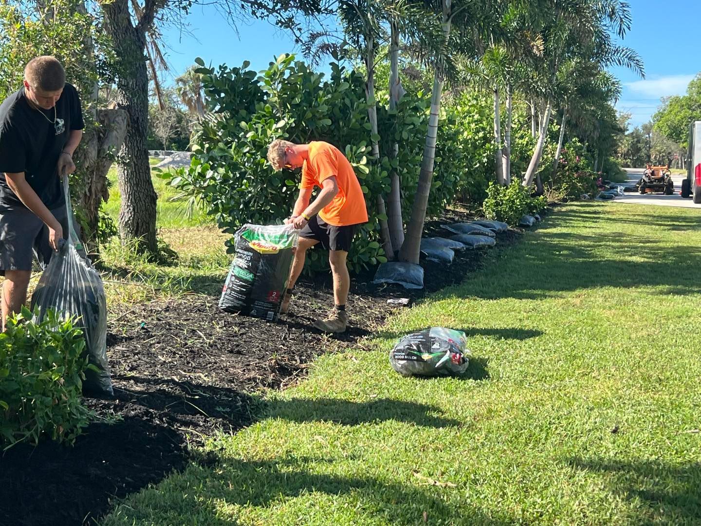 Tan stucco house with a tile roof, arched entryway, brick driveway, and manicured landscaping.
