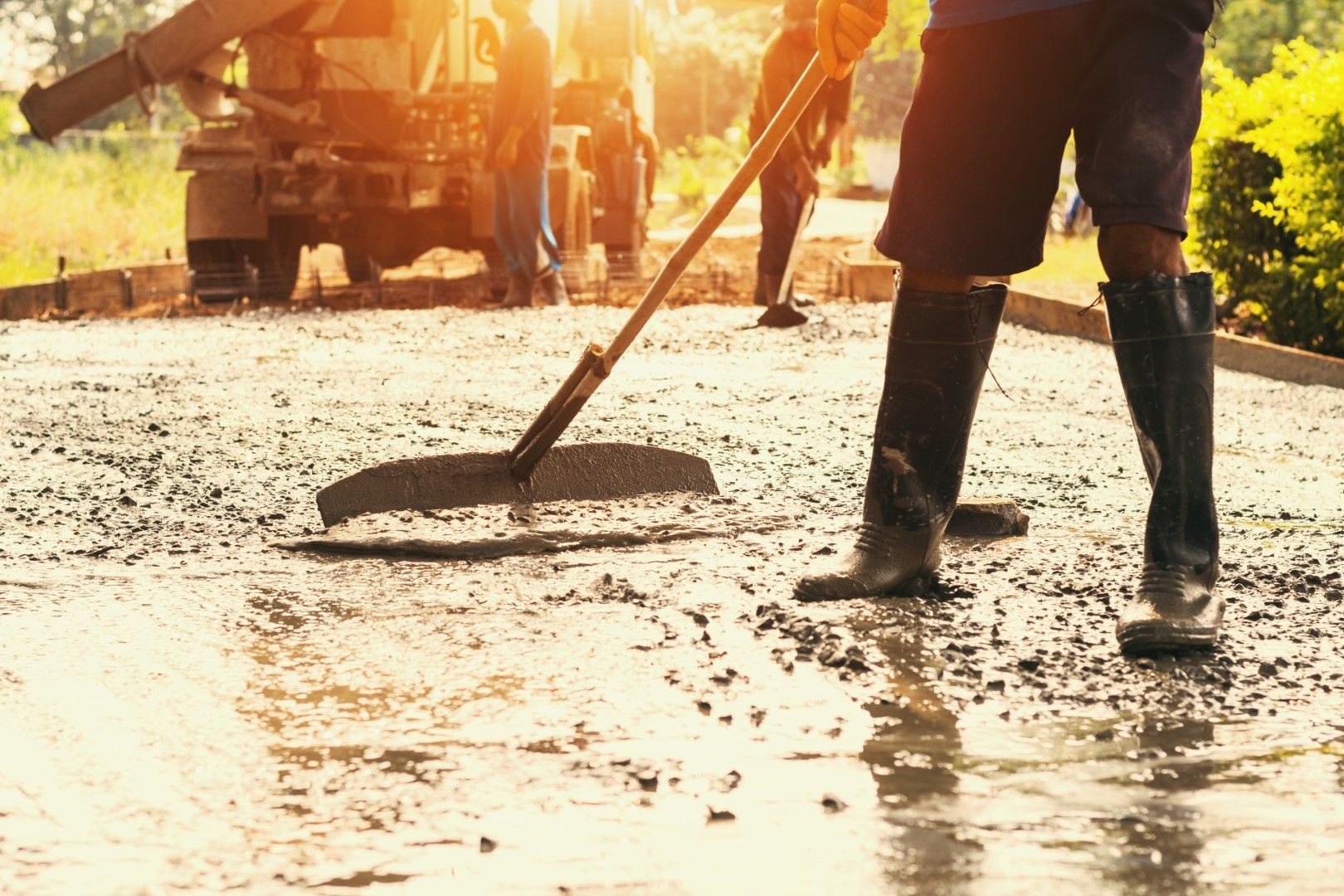A man is sweeping a concrete driveway with a broom.