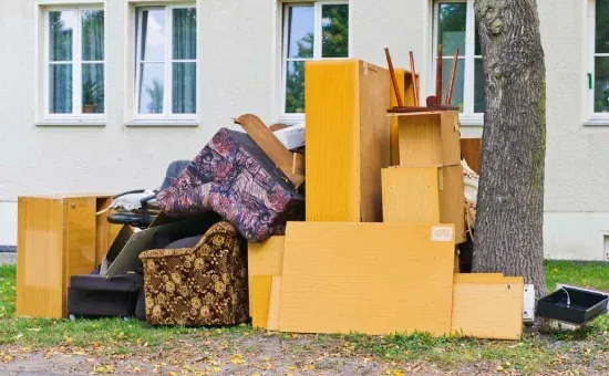 A pile of junk is sitting on the grass in front of a house.