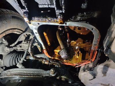 A close up of the underside of a car with oil coming out of it