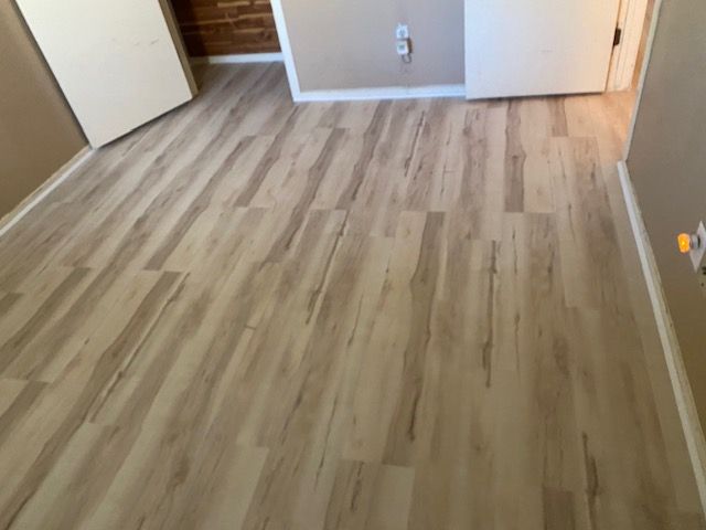 Light wood-look flooring installed in a room with white doors and beige walls.