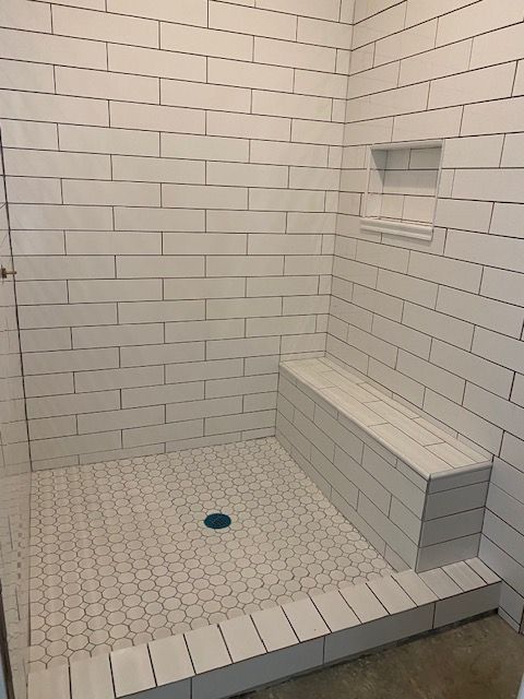 Construction site: Hole in concrete floor, exposed pipes, jackhammer, dirt, wooden frame, plumbing repairs.