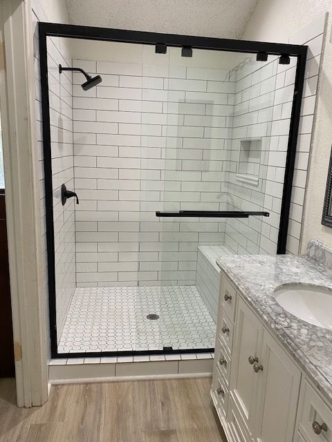 Modern bathroom with black-framed glass shower, white subway tiles, and a vanity.
