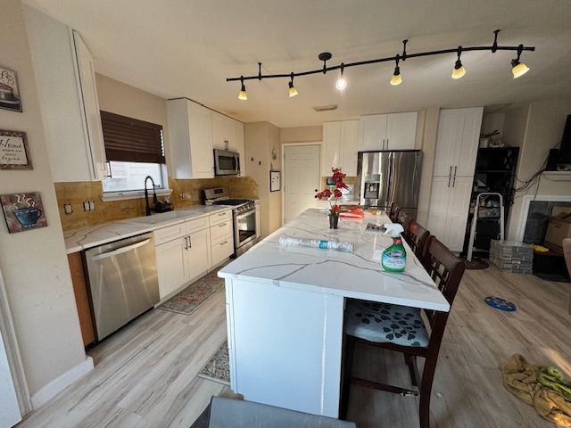 Modern kitchen with white cabinets, stainless steel appliances, and a marble-look island.