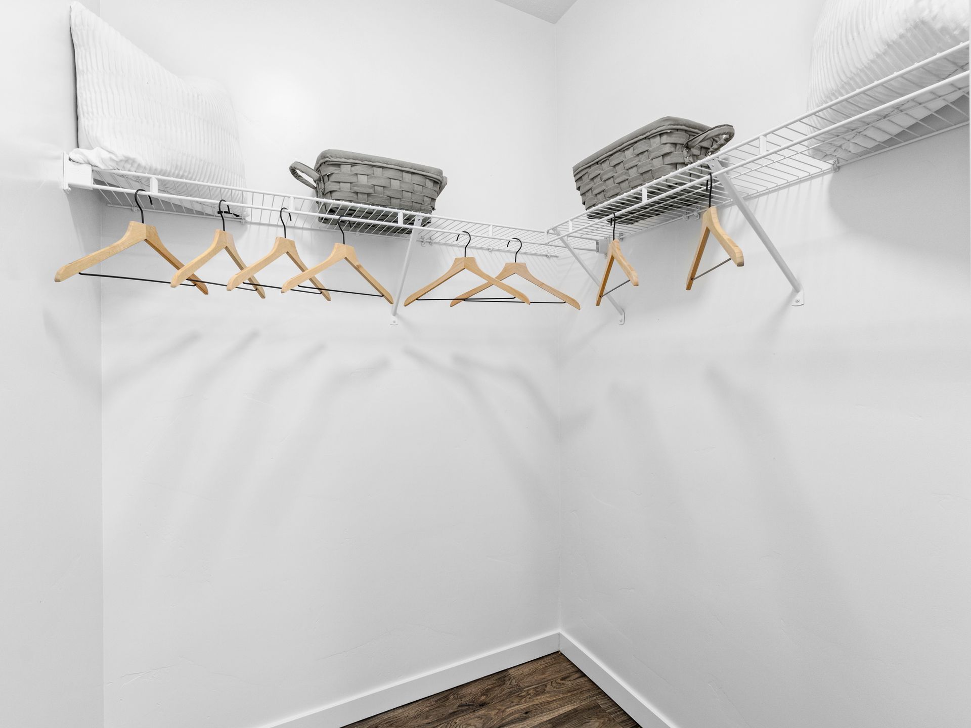 Inside a walk-in closet with a wire shelf, wooden hangers, and storage baskets.