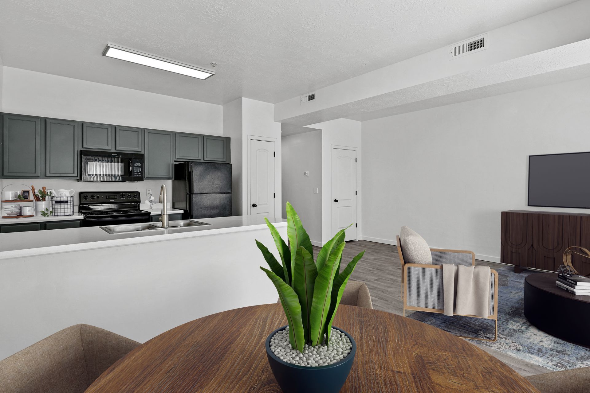 Open-concept apartment living space with a gray kitchen, island, and seating.