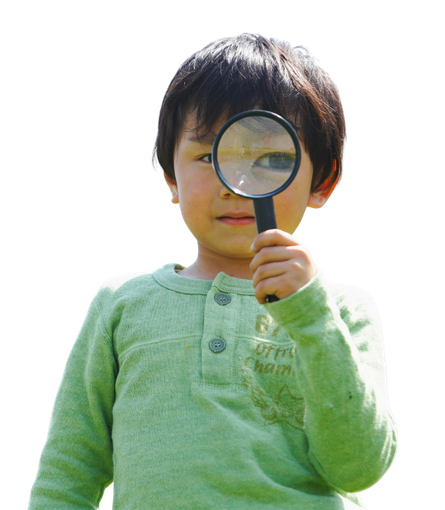 Boy in green sweater looking through magnifying glass.